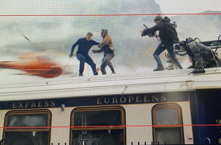 Tom Cruise acena do topo de trem em movimento enquanto filma Missão Impossível